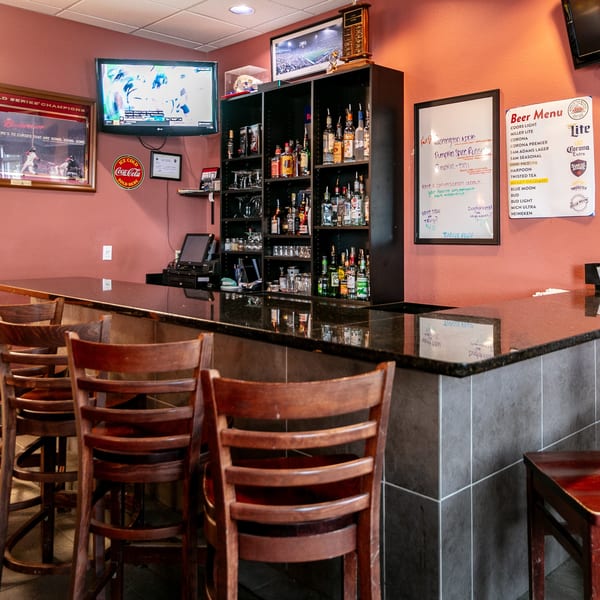Interior of Mr. G's Pizzeria bar area with stools, liquor shelves, and a beer menu.