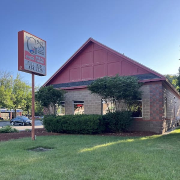 Exterior of Mr. G's Pizzeria, a brick building with a red roof and a tall sign.